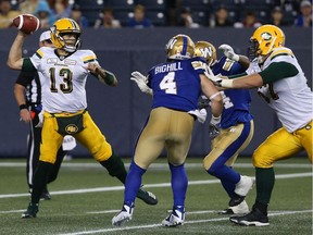 Edmonton Eskimos QB Mike Reilly throws under pressure from Winnipeg Blue Bombers LB Adam Bighill (4) and DE Tristan Okpalaugo during CFL action in Winnipeg on Thurs., June 14, 2018.