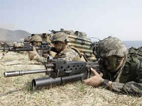 FILE - In this March 30, 2015, file photo, marines of South Korea, right, and the U.S aim their weapons near amphibious assault vehicles during U.S.-South Korea joint landing military exercises as part of the annual joint military exercise Foal Eagle between the two countries in Pohang, South Korea. U.S. President Donald Trump promised to end "war games" with South Korea, calling them provocative, after meeting North Korean leader Kim Jong Un on June 12, 2018. His announcement appeared to catch both South Korea and the Pentagon by surprise.
