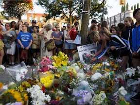 TORONTO, ON - JULY 25: People drop flowers at a memorial during a vigil for victims of Sunday night's mass shooting on Danforth Ave. on July 25, 2018 in Toronto, Canada. A 29-year-old man opened fire on restaurants and cafes in Torontos Greektown neighborhood killing a 10-year-old girl and a young woman and wounded 13 others.