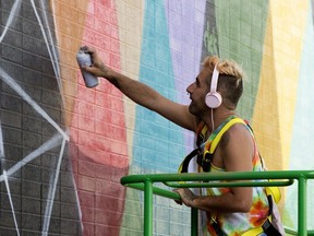 Internationally-renowned artist Okuda San Miguel paints a six-storey tall mural on the side of the Crawford Block building in Edmonton's Old Strathcona on Monday, July 16, 2018.
