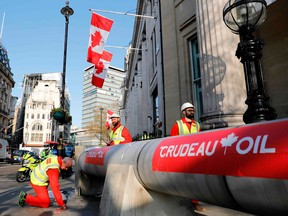 Demonstrators use a mock oil pipeline to block the entrance to the Canadian Embassy in London this spring as they protest against the Trans Mountain oil pipeline.