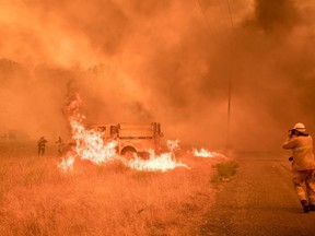 Firefighters scramble to control flames surrounding a fire truck on July 1, 2018, as the Pawnee fire jumps across highway 20 near Clearlake Oaks, California.  A Californian wildfire that began on the weekend has rapidly spread across 70,000 acres (28,000 hectares), authorities said July 3, 2018, with a growing number of areas affected by mandatory evacuation orders. The County Fire was sparked in the northern Yolo County on Saturday, fanned by high winds and hot temperatures. An update by Cal Fire on Tuesday said the potential for growth remains high as crews battle the fire in difficult terrain.