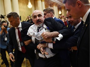 A man is escorted out of the room after displaying a placard reading "nuclear weapons ban treaty" ahead of a joint press conference of the US and Russian presidents at the Presidential Palace in Helsinki, on July 16, 2018.