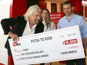 Sir Richard Branson pretends to run away with the cheques after announcing the winners Stephanie and Alexander Florio from Toronto of the first-ever Canadian edition of the Pitch to Rich contest, which asked aspiring entrepreneurs in Canada to share a mobile related business idea for their chance to win a mentor meeting with Richard Branson and $10,000 toward their business idea at the Virgin Mobile store at the CF Chinook Centre in Calgary on Tuesday May 15, 2018. Darren Makowichuk/Postmedia