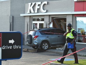 Police investigate at  the scene of a vehicle that crashed into the KFC, sending one person to hospital with a severe leg injury at 156 Street near 87 Avenue in Edmonton on Wednesday, July 18, 2018.