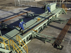 Trainees roll pipe off the catwalk during a training session to lay down drill pipe on a rig floor at Precision Drilling in Nisku.