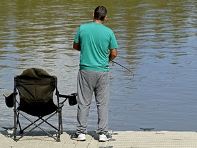 Chris Fouquette fishes off a boat dock near the Dawson Bridge in Edmonton on Sunday July 8, 2018 during the final license free fishing weekend of the year, which occurs twice a year in Alberta.