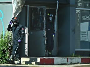 Fire investigators exit a two storey commercial building near 11725 Jasper Ave. after an early morning fire that closed down Jasper Ave. in Edmonton, July 11, 2018. Ed Kaiser/Postmedia