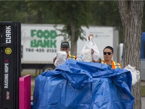 Volunteers transfer food from the drop off locations near the bus stop to a larger container for Edmonton's Food Bank at the 2017 Heritage Festival.