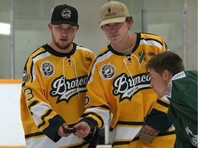 Humboldt Broncos bus crash survivors Derek Patter, left, and Tyler Smith take part in a ceremonial puck drop on Friday at Mark Messier Arena in St. Albert during a ceremony to kick off a memorial hockey tournament organized by friends of four Humboldt Broncos hockey players from St. Albert killed in a tragic bus crash — Stephen Wack, Jaxon Joseph, Logan Hunter and Conner Lukan.