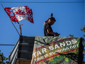 A man known as Blackwolf stands on top of a structure at Camp Cloud near the entrance of the Kinder Morgan Trans Mountain pipeline facility in Burnaby, B.C., on Saturday July 21, 2018.