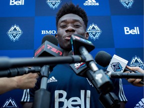 Vancouver Whitecaps midfielder Alphonso Davies is surrounded by microphones during a news conference at the MLS soccer team's training facility in Vancouver, on Thursday July 26, 2018. The Vancouver Whitecaps confirmed Wednesday that German soccer giant Bayern Munich has agreed to a transfer deal for the 17-year-old Canadian, in a move that according to the team could amount to more than $22 million US, the most ever received by an MLS club. Bayern said Davies' contract runs until 2023.