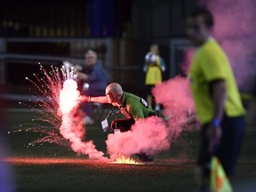 A security guard picks up a flare that was thrown onto the field in the second half of a Toronto FC-Ottawa Fury Canadian Championship match in Ottawa on July 18.