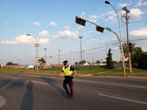 An Edmonton police officer tapes off the roadway following a fatal collision on Yellowhead Trail at 124 Street on Friday, July 27, 2018.