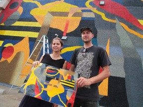 Calgary mural team Nasarimba hold their sketch upside down for a laugh in front of their 107 Avenue mural.