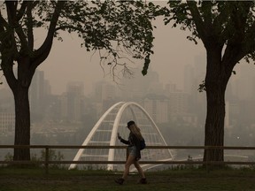 A pedestrian takes photos of the smokey Edmonton skyline from Saskatchewan Drive and 106 Street, Wednesday Aug. 15, 2018. Smoke from forest fires in British Columbia blanketed the Edmonton region Wednesday.