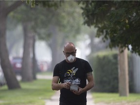 Bill Pats wears a mask to protect himself from the smoke while out promoting his Fringe Festival play Nightmare on East Hastings, near 101 Street and 85 Avenue, in Edmonton Friday Aug. 17, 2018.