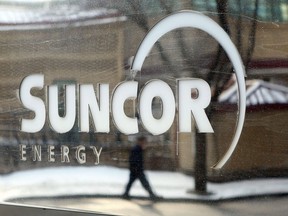 A pedestrian is reflected in a Suncor Energy sign in Calgary, Monday, Feb. 1, 2010. Suncor Energy Inc. says it is in the process of restarting production at its Edmonton refinery after it was knocked offline by a power outage on Tuesday afternoon.