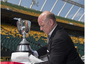 Jeff McWhinney of the Canadian Football hall of fame brings the Grey Cup out of its protective case at Commonwealth Stadium. The Edmonton Eskimos are teaming up with Purolator on Thursday, August 2, to tackle hunger as part of the Purolator Tackle Hunger program, in support of Edmonton's Food Bank on July 26, 2018. Shaughn Butts / Postmedia