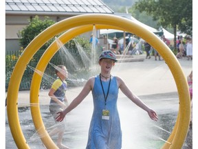 Mariah Fournier walks through the  spray park to cool down in temperatures topping out at 34 C at the Edmonton Folk Music Festival site in Gallagher Park on Thursday, Aug. 9, 2018.