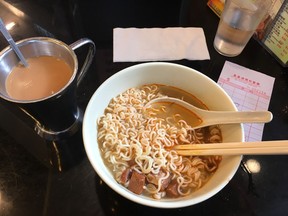 Cubes of roast beef mingle with noodles in a bowl of tasty broth, served alongside hot, milky tea at Hay Hay restaurant in Hong Kong.
