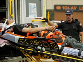 A handcuffed suspect is transported by ambulance to hospital after a shooting incident and police chase that ended on 75 Street near 101 Avenue on Wednesday August 15, 2018. (PHOTO BY LARRY WONG/POSTMEDIA)