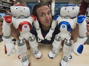 U of A PhD student Kory Mathewson with the two robots he will be using in an improv show at this year's Edmonton International Fringe Festival.