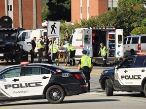Police officers and paramedics survey the area of a shooting in Fredericton, N.B. on Friday, August 10, 2018.