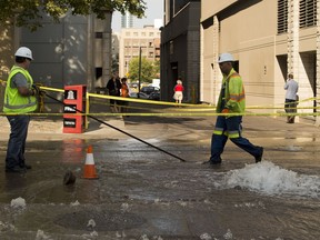 Epcor workers inspect the area where the street flooded after a watermain break near the corner of 109 street and Jasper Avenue on Wednesday, Aug. 1, 2018 in Edmonton.