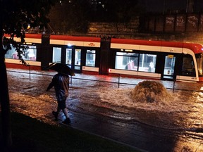 Water overflows from heavy rain, stopping a streetcar on King St. W. in Toronto on Tuesday, August 7, 2018.