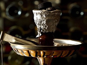 Joseph Rustom, owner of Parkallen Restaurant, demonstrates the use of a hookah at his restaurant in Edmonton on April 11, 2013.