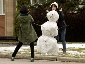 Passersby take photos with a snowman at the University of Alberta, in Edmonton Friday Sept. 21, 2018. Friday marked the last day of summer.