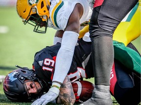 Calgary Stampeders quarterback Bo Levi Mitchell is tackled by Alex Bazzie of the Edmonton Eskimos during the Labour Day Classic in Calgary on Monday, September 3, 2018.