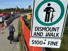 A new sign has gone up indicating a $100 fine for cyclists riding over on the narrow shared sidewalk lane over the Groat Road Bridge which is under construction in Edmonton on Thursday, Sept. 6, 2018.