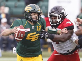 Calgary Stampeders Micah Johnson (4) grabs Edmonton Eskimos quarterback Mike Reilly (13) during first half CFL action at Commonwealth Stadium on Saturday, Sept. 8, 2018.