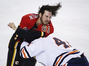 Calgary Flames player Scott Sabourin, left, fights Evan Polei of the Edmonton Oilers during first period preseason NHL hockey action in Calgary on Monday, Sept. 17, 2018.