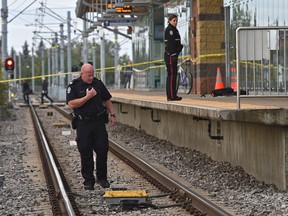 A police officer walks on the tracks looking for a weapon while a backpack and jacket lies on the platform where a young man was stabbed while waiting on the platform of the South Campus LRT station in Edmonton on Tuesday,  Sept. 18, 2018.