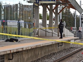 A police officer stands on the platform as a backpack and jacket lie where a young man was stabbed while waiting on the platform of the South Campus LRT station in Edmonton on Tuesday, Sept. 18, 2018.