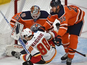 Calgary Flames Andrew Mangiapane gets pushed off his skates by Edmonton Oilers Darnell Nurse (25) in front of goalie Cam Talbot (33) during pre-season NHL action at Rogers Place in Edmonton, September 29, 2018. Ed Kaiser/Postmedia