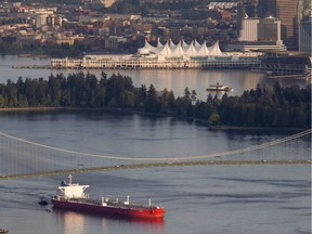 An oil tanker is guided by tug boats as it goes under the Lions Gate Bridge at the mouth of Vancouver Harbour on May 5, 2012.