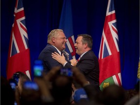 Ontario Premier Doug Ford, left, and United Conservative Leader Jason Kenney embrace on stage at an anti-carbon tax rally in Calgary, on Friday October 5, 2018. Leah Hennel/Postmedia