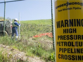 A worker installs new fence posts surrounding the Burnaby B.C., Kinder Morgan location Thursday, April 26, 2018.