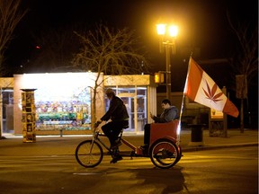 A cyclist and a passenger celebrate marijuana legalization near Whyte Avenue and Gateway Blvd, after midnight in Edmonton Wednesday Oct. 17, 2018.