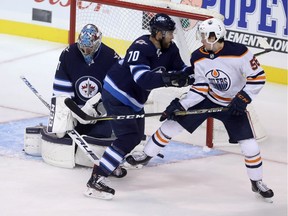 Edmonton Oilers forward Kailer Yamamoto (56) tips a shot past Winnipeg Jets' goaltender Connor Hellebuyck (37) as he's checked by Joe Morrow (70) during first period preseason NHL hockey action in Winnipeg, Sunday, September 23, 2018.