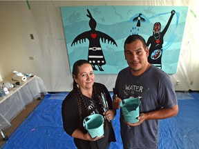 Artists Christi Belcourt, left, and Isaac Murdoch have almost completed a painting for MacEwan University's Indigenous Centre in Edmonton, on Tuesday, Oct. 30, 2018. The artists are creating works of art across the country to raise funds for a language and arts camp for Indigenous youth.
