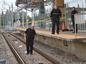 A police officer walks on the tracks looking for a weapon while on the platform (R) a backpack and jacket lay where a young man was stabbed while waiting on the platform of the South Campus LRT station in Edmonton, September 18, 2018.