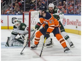 Connor McDavid of the Edmonton Oilers, looks for a play as he rounds the net beside Devan Dubnyk of the Minnesota Wild at Rogers Place in Edmonton on March 10, 2018.