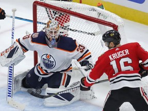 Chicago Blackhawks forward Marcus Kruger, right, swings at the bouncing puck in front of Edmonton Oilers goalie Cam Talbot during NHL action on Oct. 28, 2018, in Chicago.