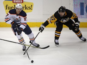 Edmonton Oilers' Connor McDavid (97) and Pittsburgh Penguins' Sidney Crosby (87) battle for a loose puck in the first period of an NHL hockey game in Pittsburgh, Tuesday, Oct. 24, 2017.