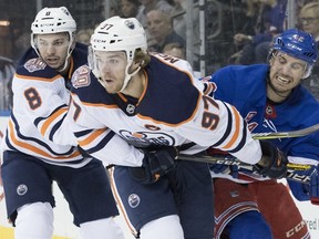 Edmonton Oilers right wing Ty Rattie (8), center Connor McDavid (97) and New York Rangers defenseman Brendan Smith (42) vie for a loose puck during the first period of an NHL hockey game, Saturday, Oct. 13, 2018, at Madison Square Garden in New York.